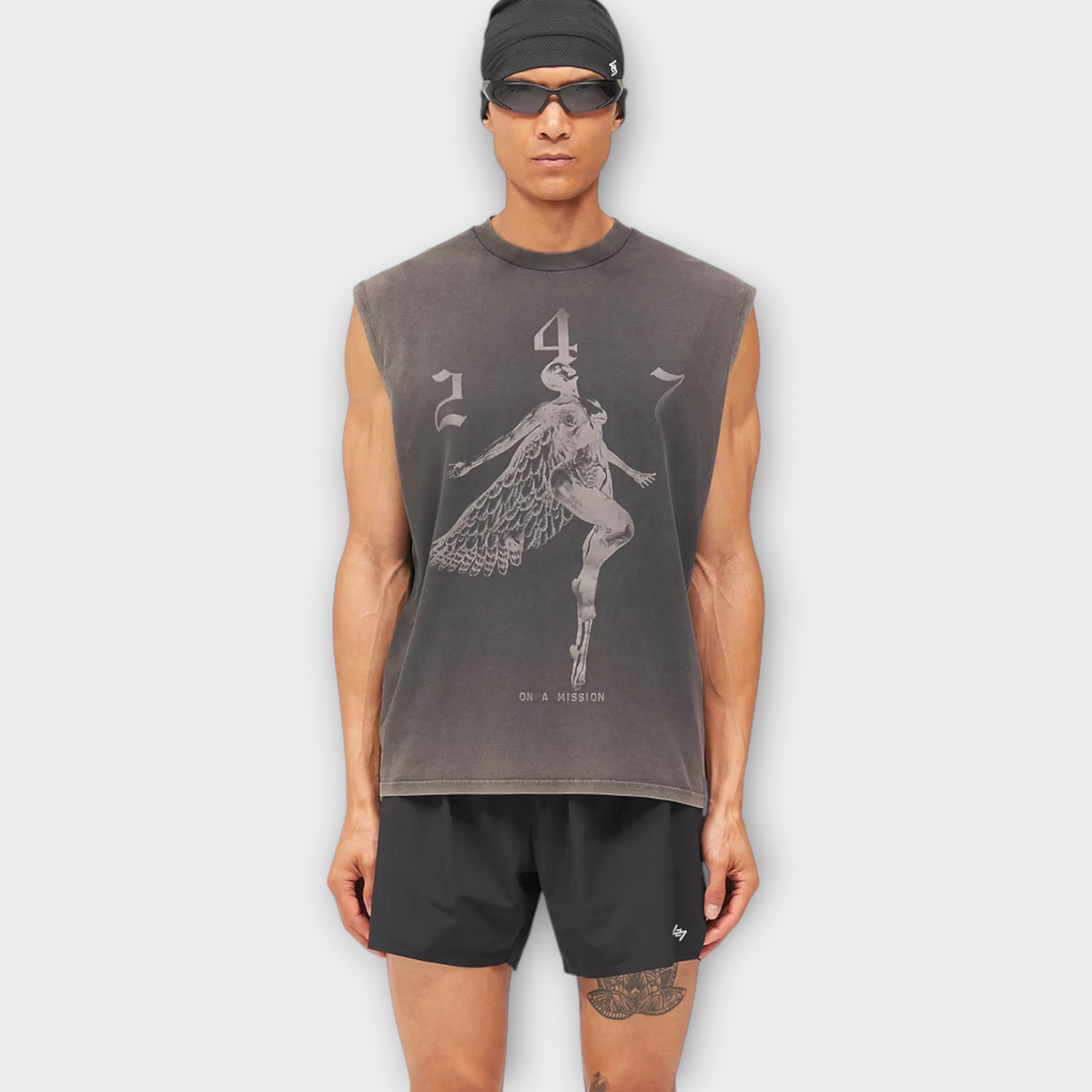 Drop 247 Angel Graphic Tank in vintage black worn by a model with a black beanie and sunglasses