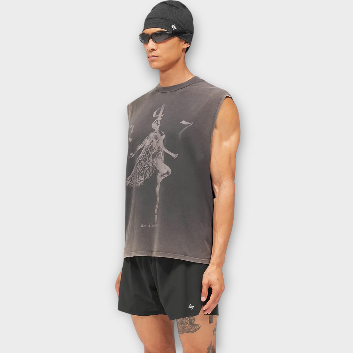Drop 247 Angel graphic tank top in vintage black worn by a model with a black beanie and sunglasses