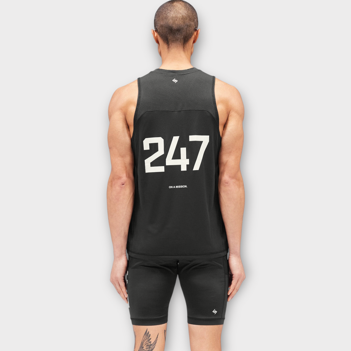 Back view of a man wearing a Drop 247 FW26 Numbers Vest in jet black with white graphic print on the back