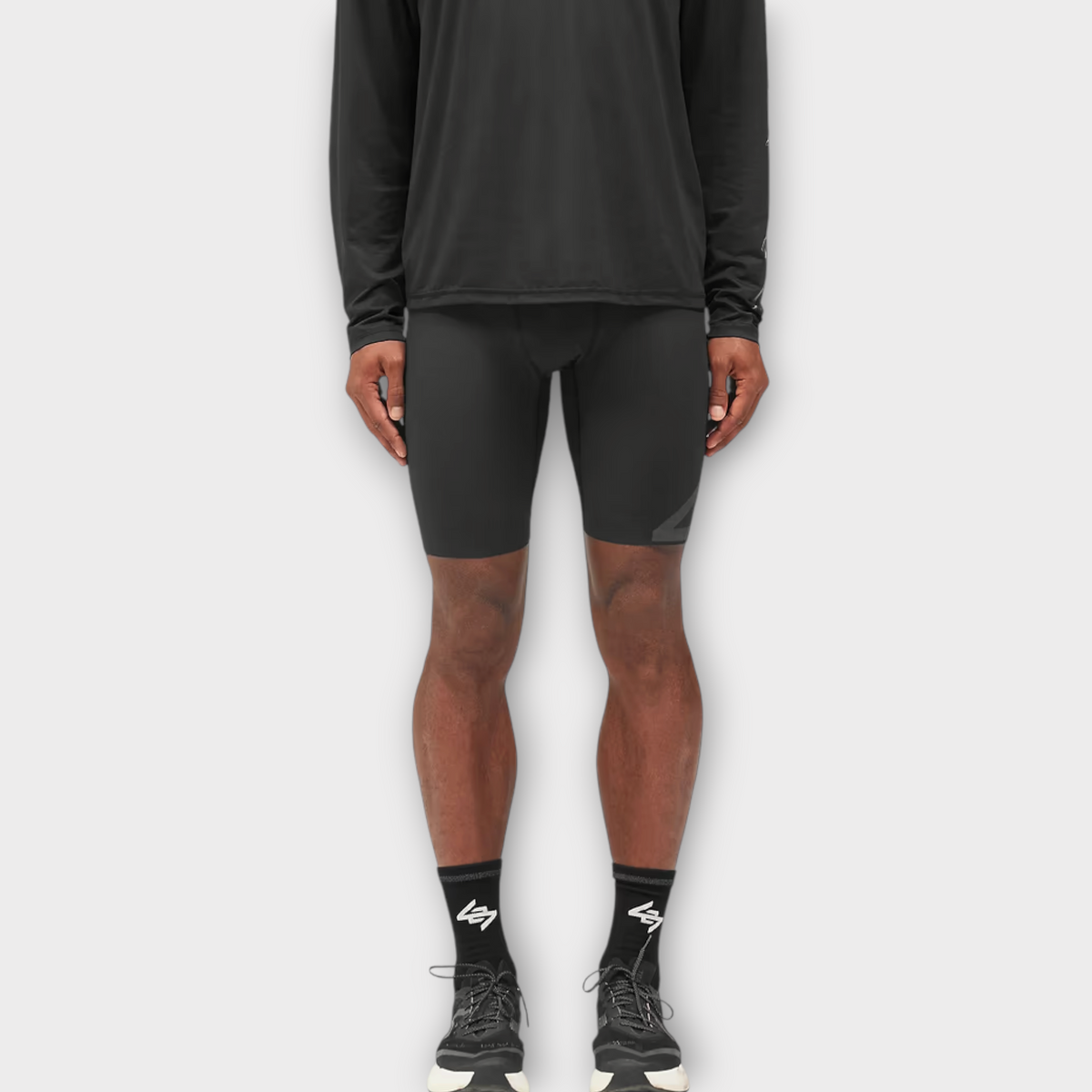 Drop 247 Ghost Short in jet black, a form-fitting athletic compression short worn by a model with black sneakers.