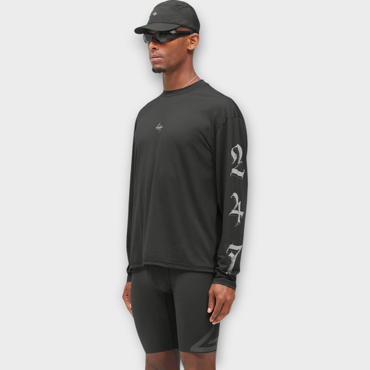 Drop 247 Knight long sleeve tee in jet black with gothic sleeve graphics worn by a model in a cap and sunglasses