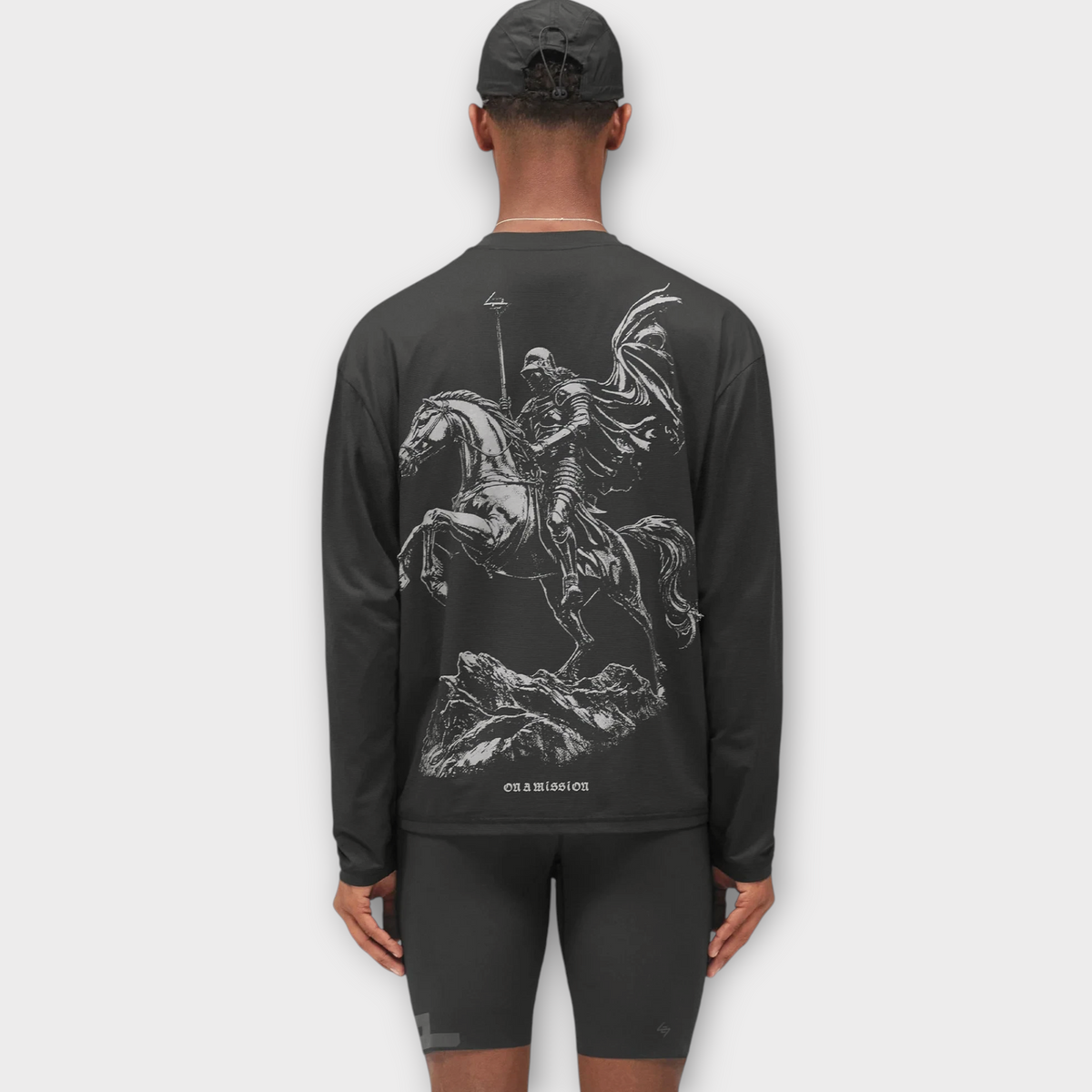 Model wearing a Drop 247 Knight Ls Tee in jet black with a detailed white graphic of a knight on horseback on the back