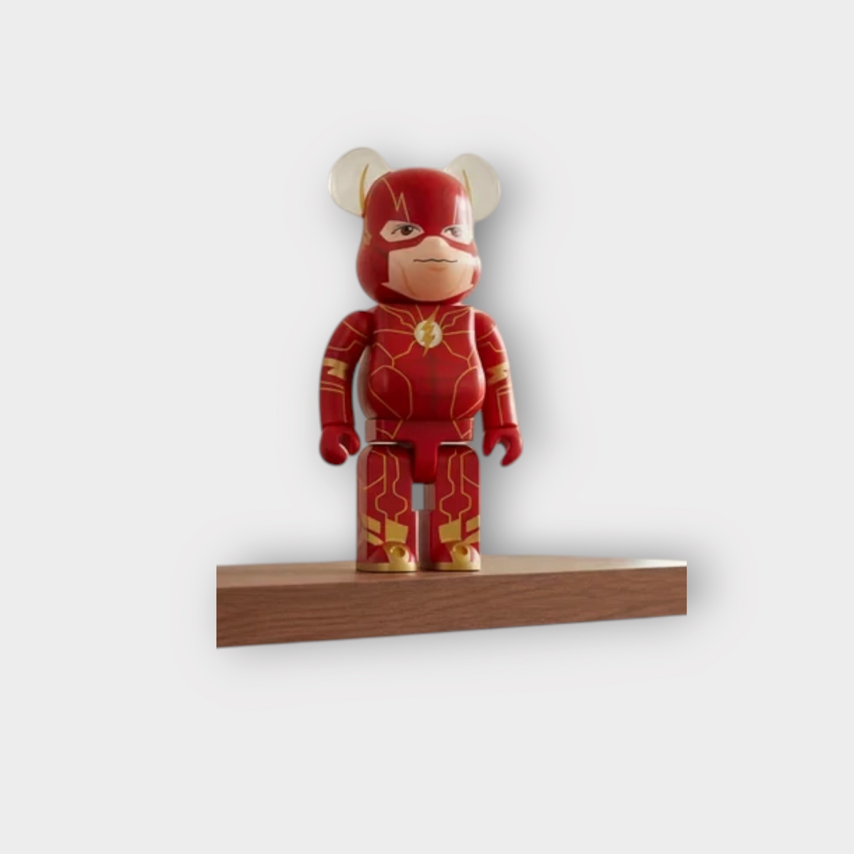 Drop Bearbrick 400% The Flash collectible figure in red and gold displayed on a wooden shelf in a modern living room.
