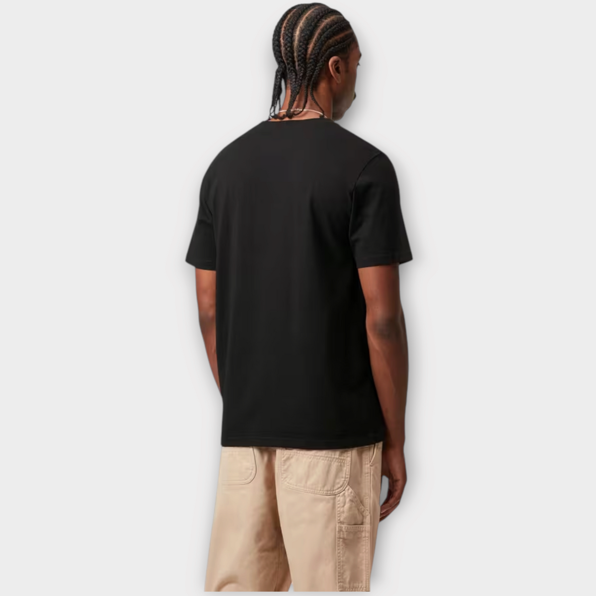 Model seen from behind wearing a black Carhartt WIP short sleeve pocket t-shirt with beige utility shorts