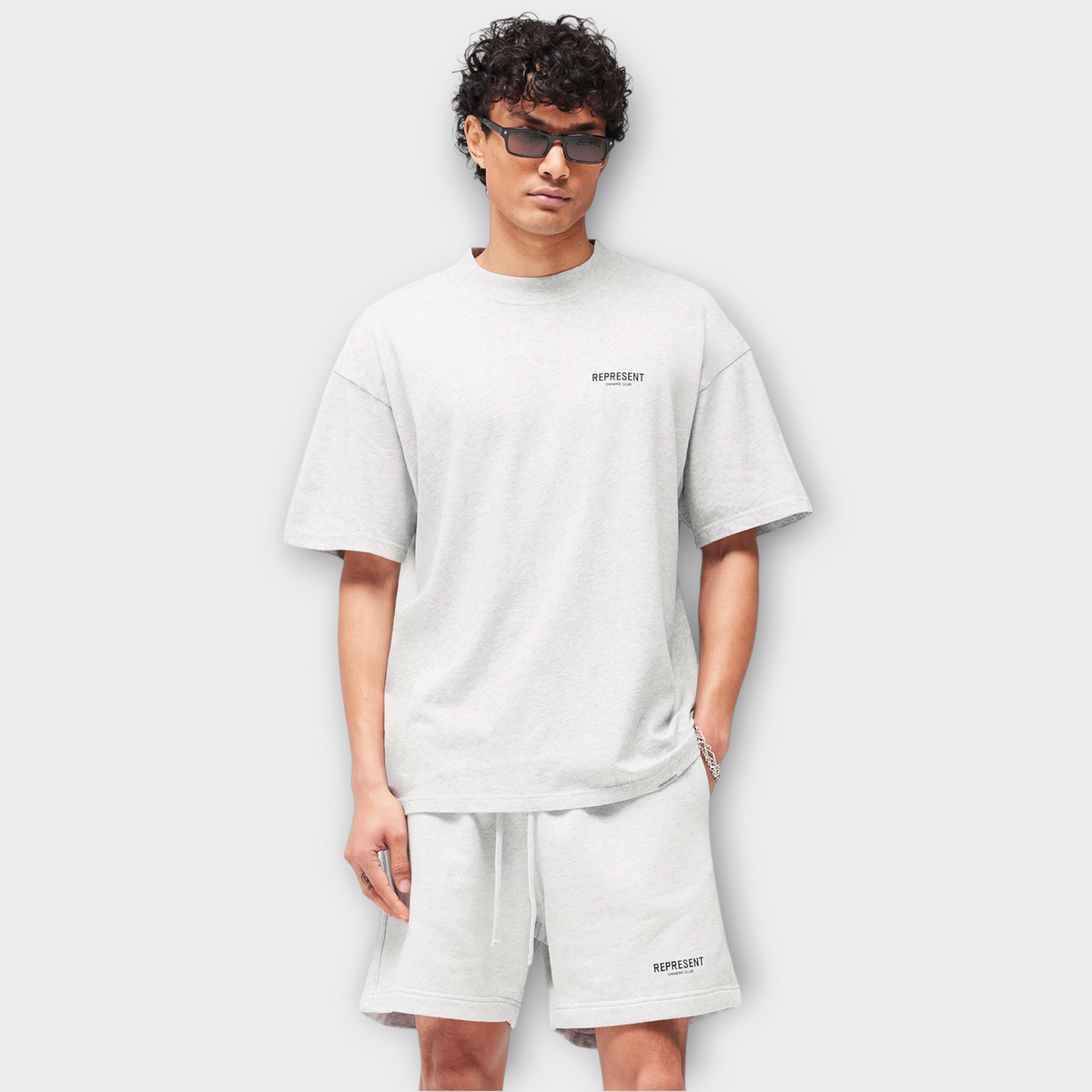 Drop Represent Owners Club ash grey t-shirt with black logo print worn by a model in sunglasses