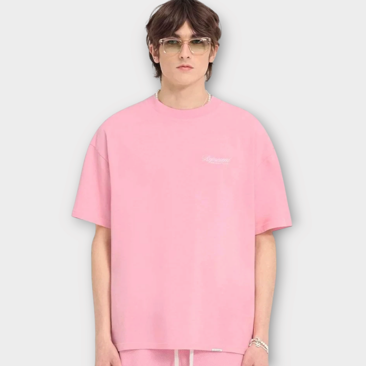 Drop Represent Owners Club script pink t-shirt worn by a male model with glasses